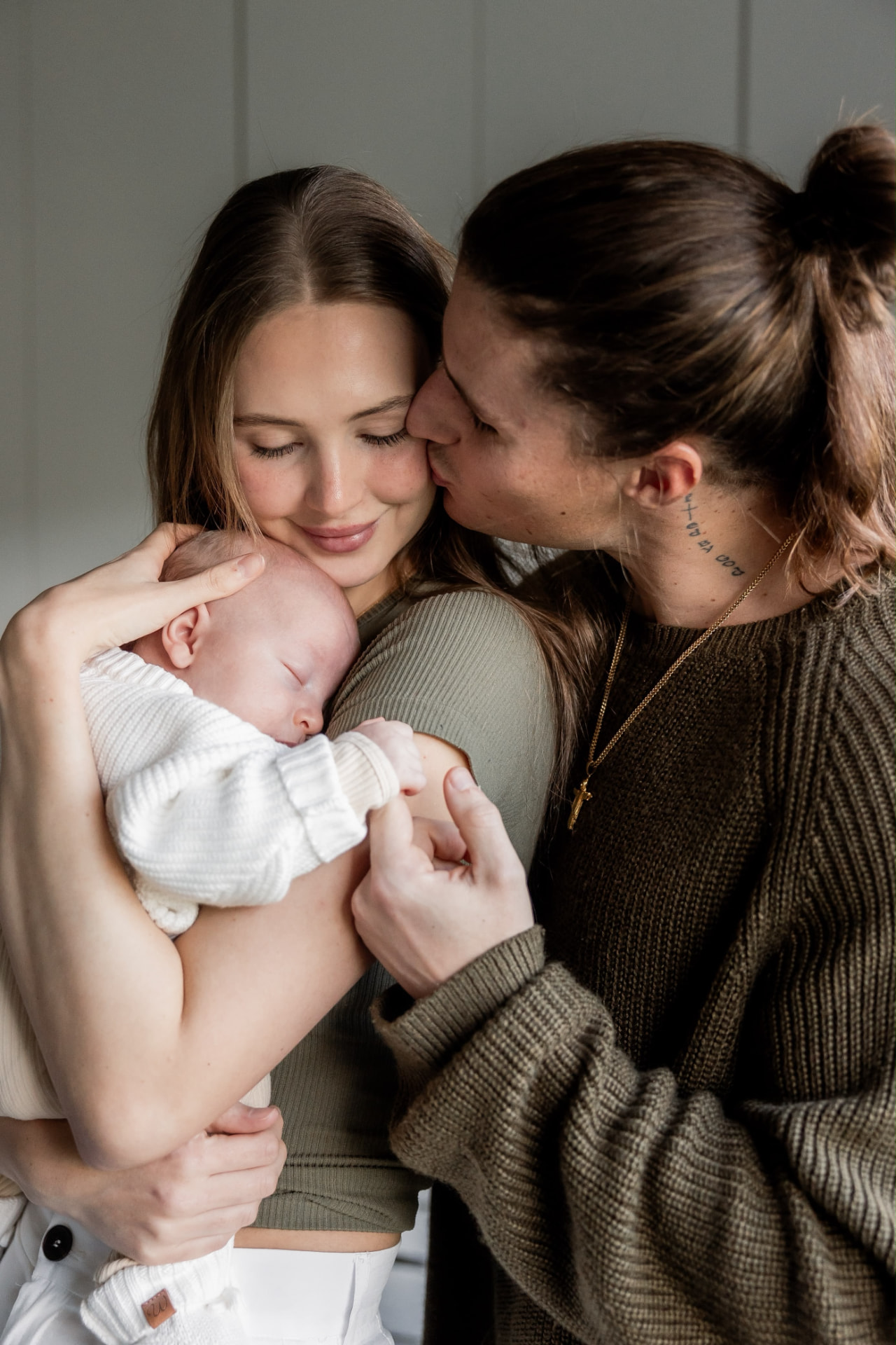 Timon kissing his wife who is holding their newborn son